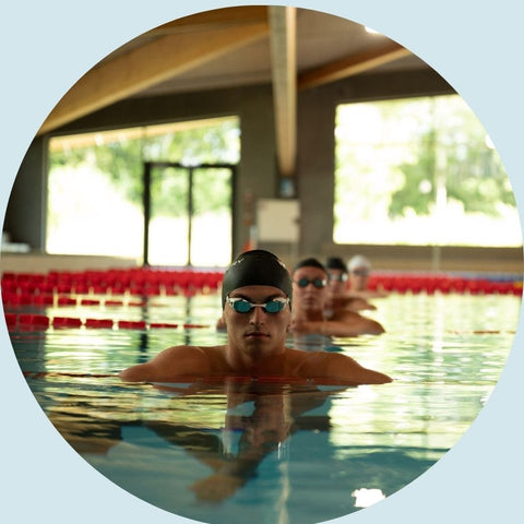 Mand med svømmebriller og badehætte i svømmehalsbane.