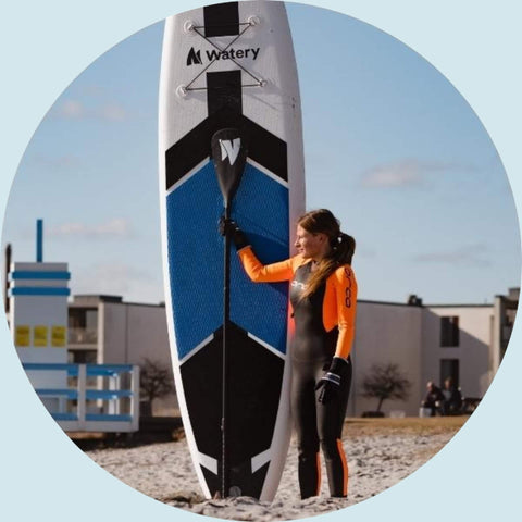 Kvinde med våddragt på holder paddle til paddleboard.